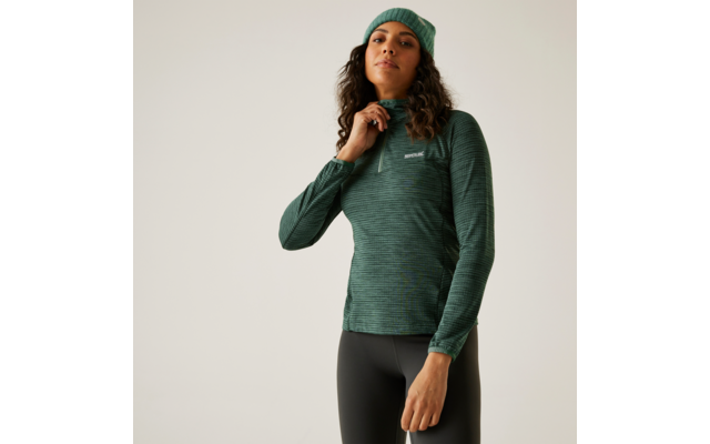 Femme portant un bonnet vert et un pull vert debout devant un fond clair