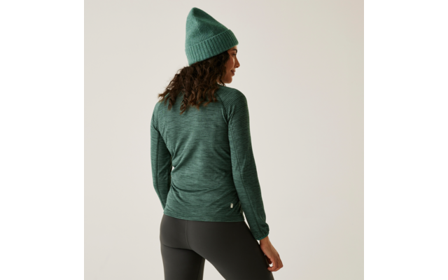 Frau von hinten mit grünem Pullover, schwarzer Leggings und grüner Mütze vor beigem Hintergrund