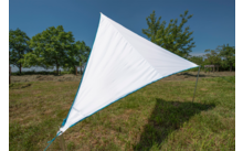 Weiße, dreieckige Sonnensegel auf einer Wiese, im Hintergrund Bäume und blauer Himmel