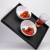 Schwarzes Tablett mit zwei weißen Schalen mit Erdbeeren und einem Glas mit roter Flüssigkeit