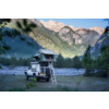 Geländewagen mit Dachzelt, aufgebaut neben einem Fluss und umgeben von Bergen und Wald