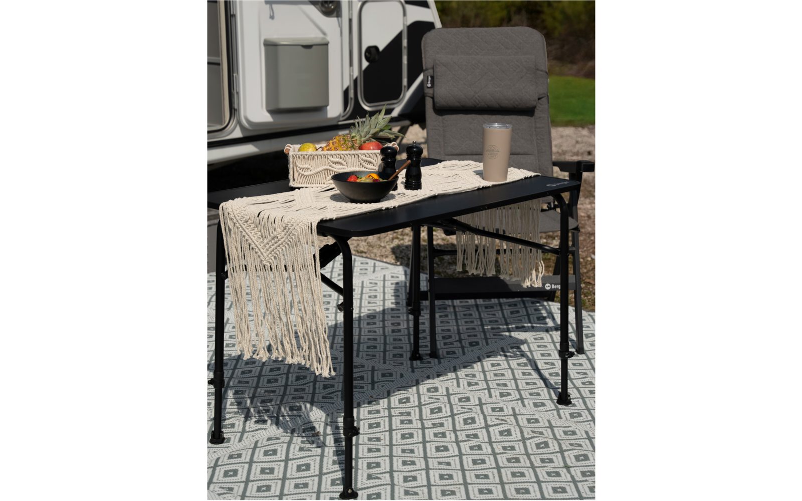 Chaise et table avec nappe et bouteille devant une caravane en plein air