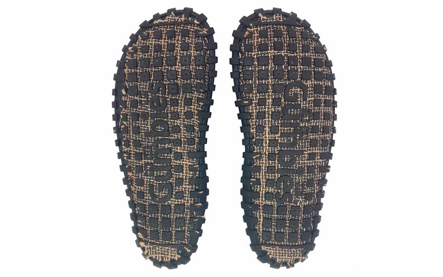 Two shoe soles with undersides visible on a white background; black rubber outsoles with rectangular tread blocks along the edges and beige woven areas visible through a grid pattern