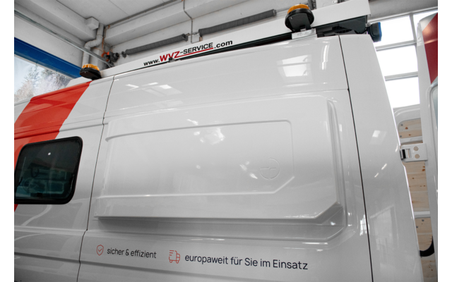 Weiße Einsatzfahrzeug-Seitenansicht mit rotem Streifen und Fenstern in einer Halle