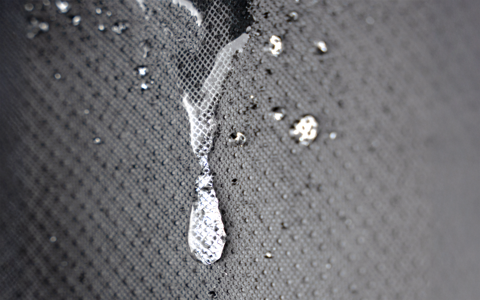 Gota transparente y pequeñas salpicaduras sobre una superficie gris texturizada