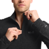 Unterer Gesichtsbereich, Hals und Oberkörper einer Person, die mit beiden Händen den Reißverschluss eines dunklen Jack Wolfskin-Fleecepullovers hochzieht; Logo auf Brust und Ärmel; Ring an einem Finger