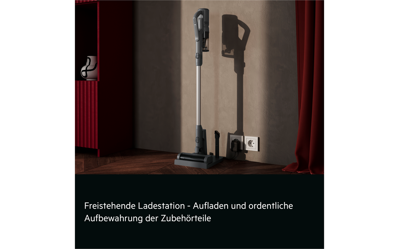 Stick vacuum in a freestanding dock beside a wall outlet, two accessories on the floor, red cabinet left, red curtain right, wooden floor, gray wall