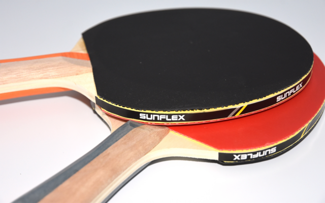 Zwei Tischtennisschläger liegen übereinander auf einem weißen Untergrund