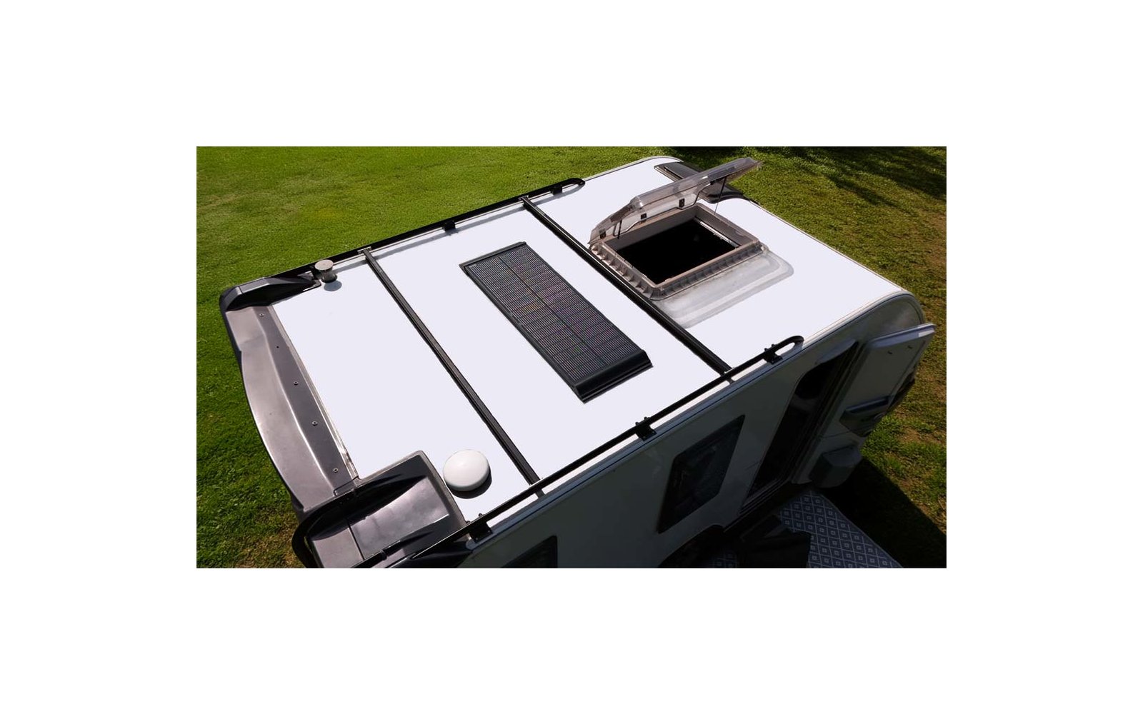 Camper bianco visto dall'alto con finestra del tetto aperta, su erba verde