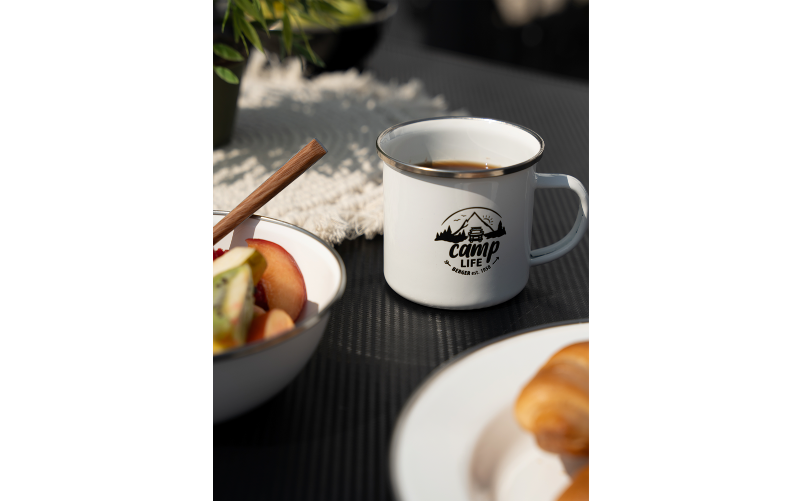 Tasse de café, bol avec des fruits à côté, croissant sur une assiette au premier plan