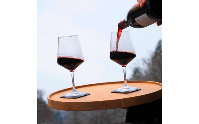 Deux verres à vin sur un plateau, l’un est rempli de vin rouge