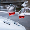Deux verres à vin inclinés avec du vin rouge sur une surface blanche, arrière-plan flou