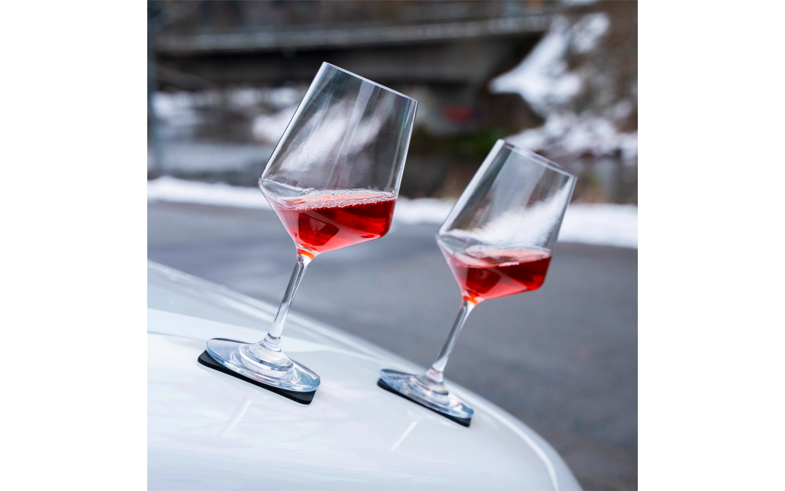 Deux verres à vin inclinés avec du vin rouge sur une surface blanche, arrière-plan flou