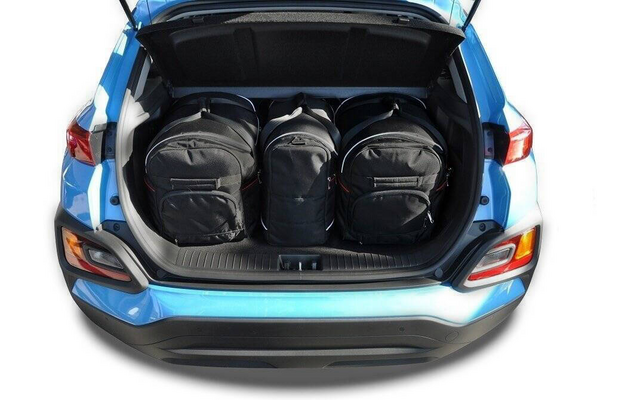 Offener Kofferraum eines blauen Autos mit drei schwarzen Rucksäcken nebeneinander