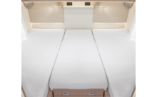 Drei weiße Matratzen nebeneinander in einem hellen Raum mit Holzschubladen darunter