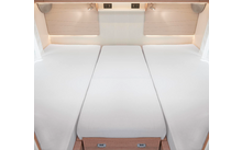 Trois matelas blancs côte à côte dans une pièce lumineuse avec des tiroirs en bois en dessous