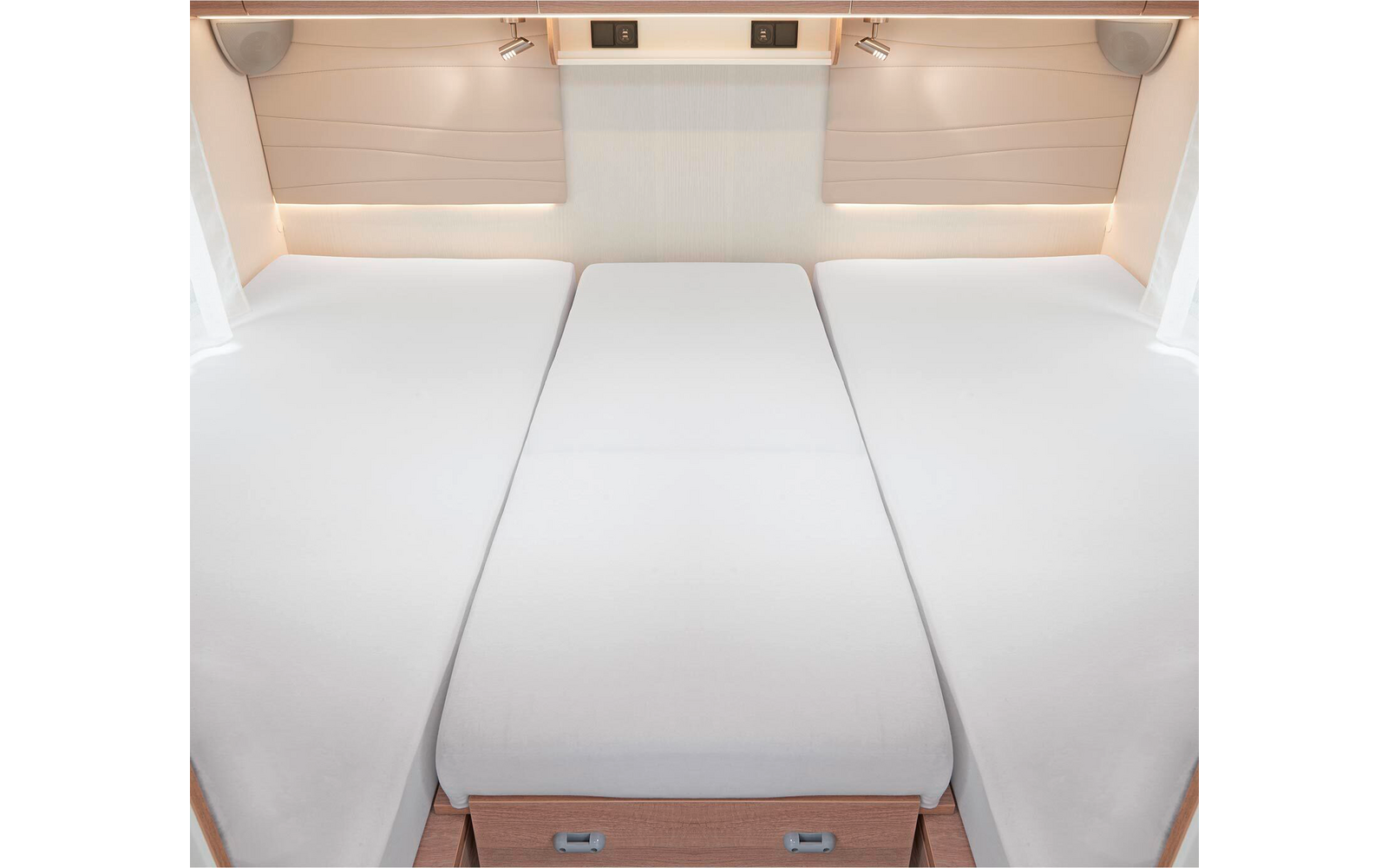 Trois matelas blancs côte à côte dans une pièce lumineuse avec des tiroirs en bois en dessous