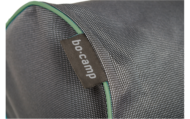 Gros plan sur un tissu gris finement structuré avec passepoil vert et une étiquette en tissu brune avec texte blanc 'bo-camp'