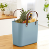 Blaue Einkaufstasche mit Ananas, Bananen und Blumentopf auf einem Holztisch