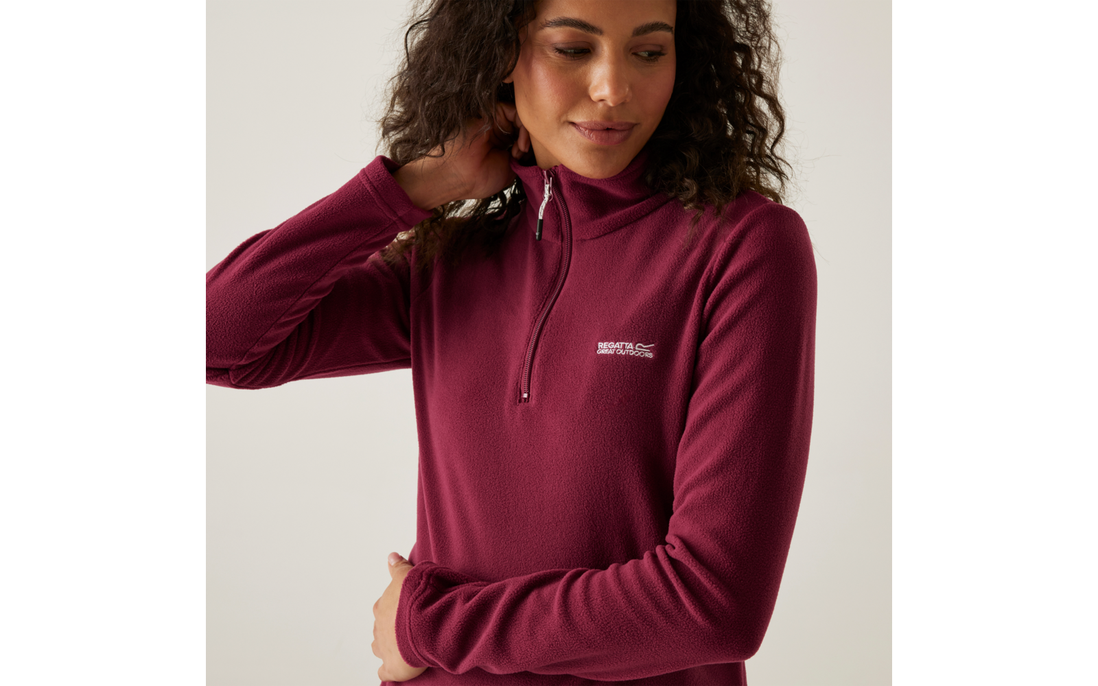 Frau in bordeauxrotem Pullover mit Reißverschluss und Logo auf der Brust