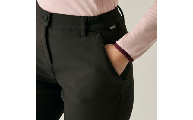 Close-up: rechterhand in de voorzak van een zwarte broek; lichtroze longsleeve met donkere boord, zichtbare tailleband, zijrits en klein merkje