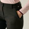 Close-up: rechterhand in de voorzak van een zwarte broek; lichtroze longsleeve met donkere boord, zichtbare tailleband, zijrits en klein merkje