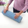 Person rollt eine blaue Yogamatte auf einem weißen Tisch zusammen