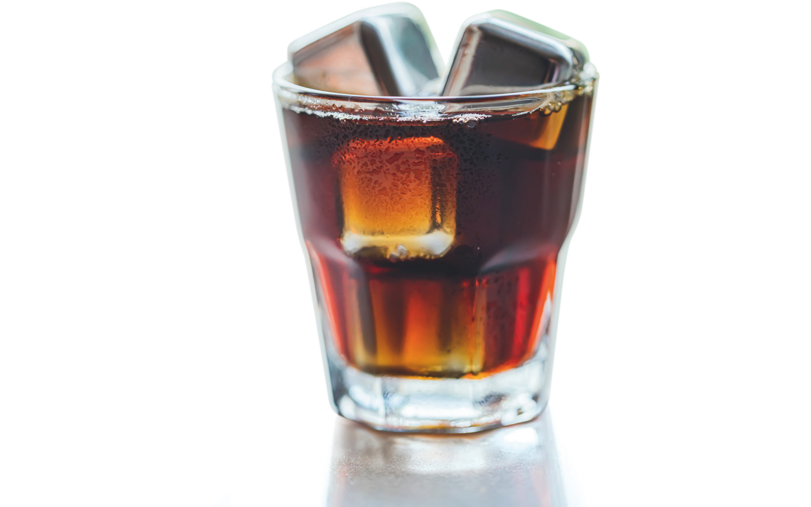Kurzes durchsichtiges Glas mit dunkelbraunem Getränk und Eiswürfeln auf hellem Hintergrund