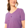 Oberkörper einer Frau mit zusammengebundenen braunen Haaren, sie trägt ein violettes V-Ausschnitt-T-Shirt mit dezentem Linienmotiv einer Blume, weißer Hintergrund