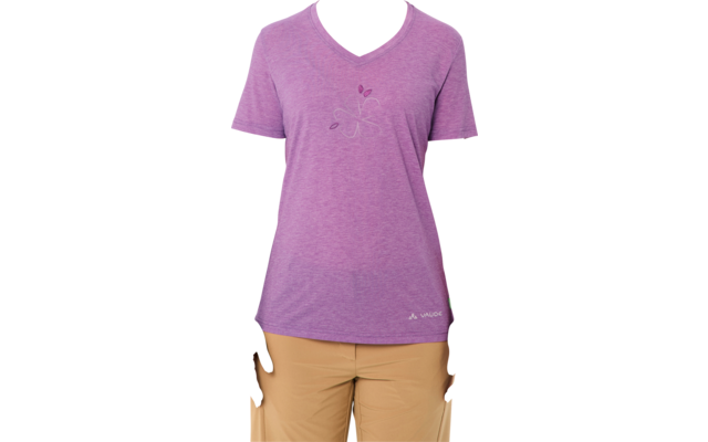 Woman standing facing camera against white background, wearing purple V-neck T-shirt with small floral print, beige pants, hair tied back, hands at sides