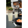 Tisch mit zwei Gläsern Limonade, schwarzen Tellern und Besteck im Freien