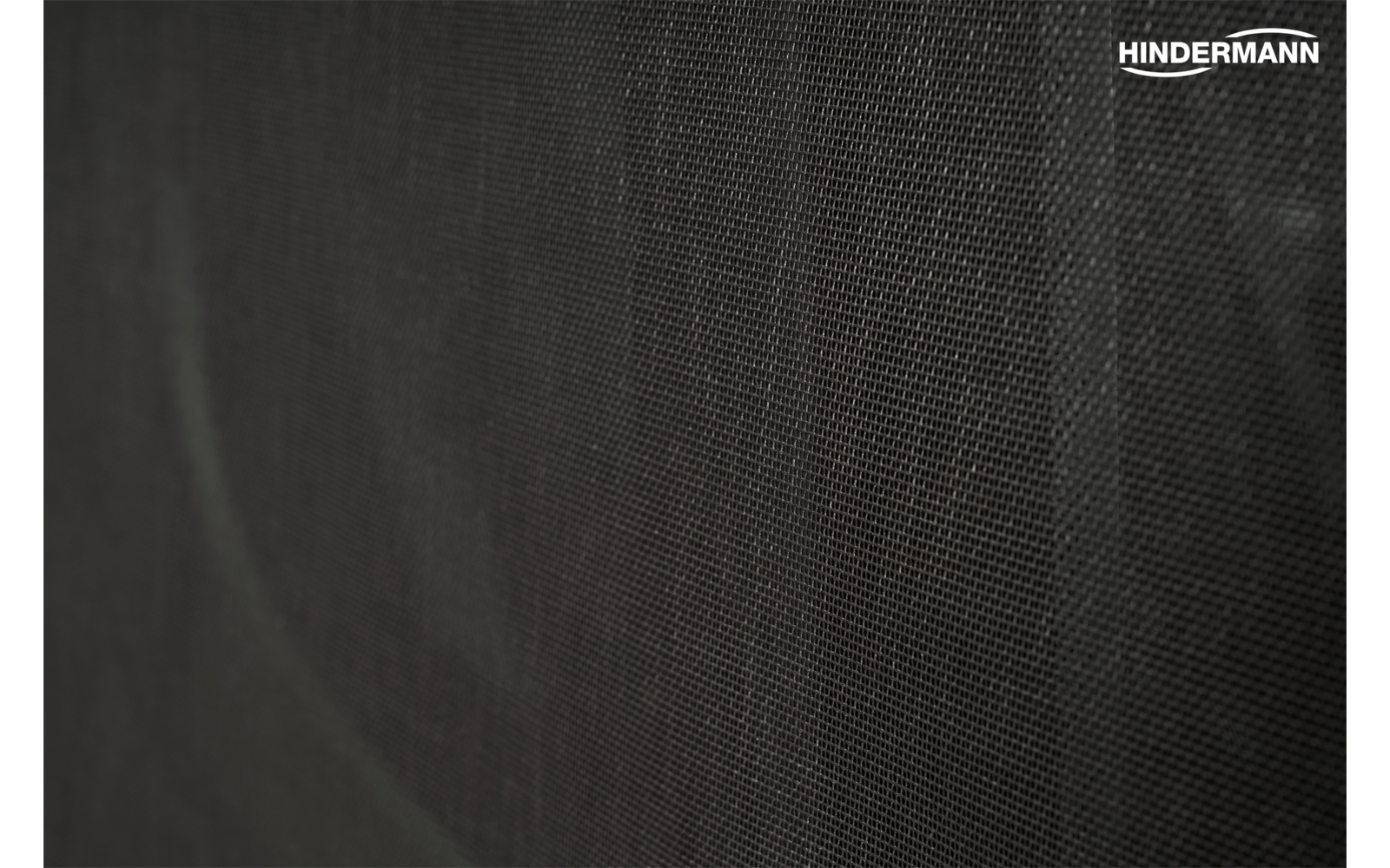 Materiale scuro a trama grossa con motivo a reticolo sottile; scritta bianca 'HINDERMANN' in alto a destra