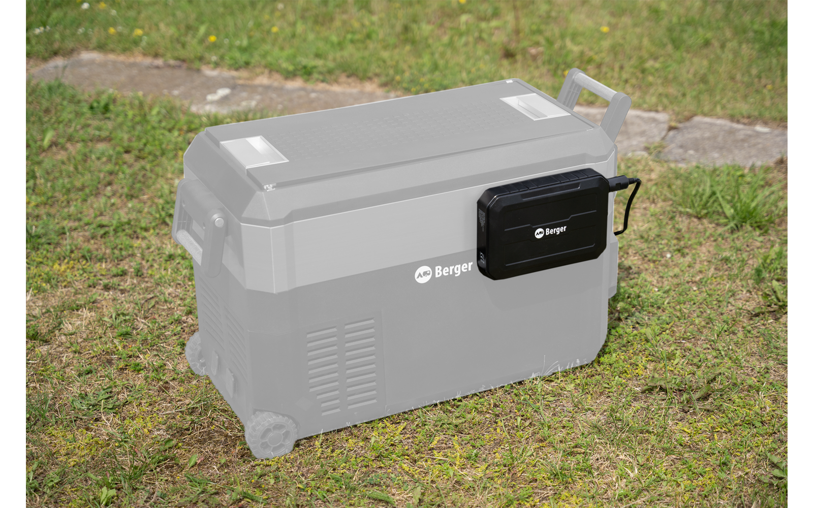 Nevera de camping negra con ruedas y asas sobre césped