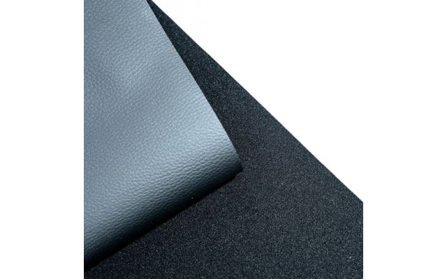 Coin replié d'un matériau gris-bleu à texture grainée sur un support noir texturé, fond blanc