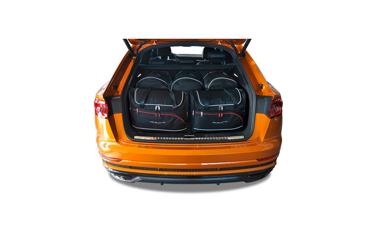 Offener Kofferraum eines orangefarbenen Autos mit vier schwarzen Reisetaschen mit weißer Ziernaht und roten Reißverschlüssen