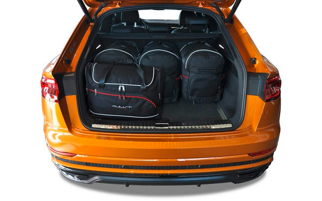 Geöffneter Kofferraum eines orangefarbenen Autos mit drei schwarzen Taschen