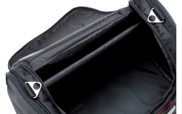 Offene schwarze Tasche mit Reißverschluss, Blick ins Innenfach mit Stofftrennwand, zwei silberne Reißverschluss-Schieber sichtbar