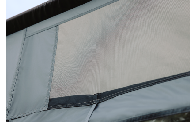 Close-up van een lichtgrijs stoffen paneel met een rechthoekig gaasvenster en zichtbare naden