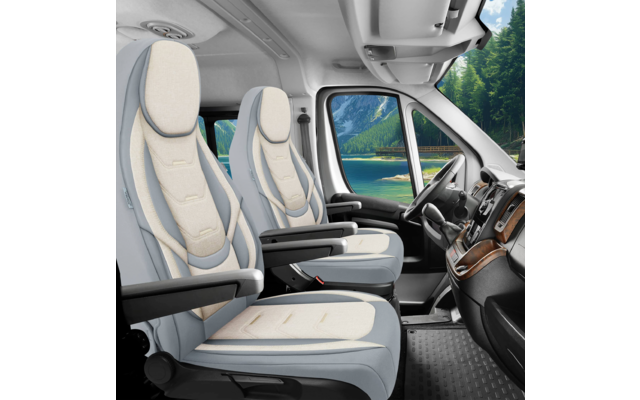 Innenraum einer Fahrzeugkabine mit zwei hellen Vordersitzen mit Armlehnen, Lenkrad, Armaturenbrett und seitlichem Fenster mit Blick auf einen See und bewaldete Berge