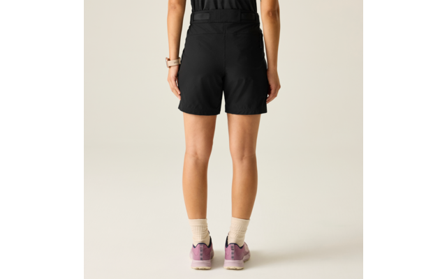 Vista posterior de una persona con pantalones cortos negros, calcetines cortos claros y zapatillas rosas sobre un fondo claro