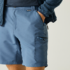 Bas du torse et cuisses d'une personne, short bleu avec poche zippée sur la cuisse, main droite dans la poche, pull bleu foncé visible