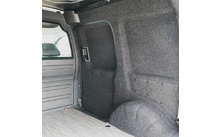 Innenraum eines Lieferwagens mit grauer Filzverkleidung, Radkasten, Trennwand mit kleinem Fenster und hellem Holzfußboden