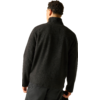 Person von hinten, trägt schwarze Fleecejacke mit Stehkragen und dunkle Hose vor hellem Hintergrund
