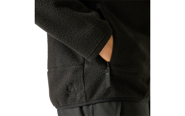 Schwarze Fleecejacke, rechte Hand in Reißverschlusstasche, sichtbarer Reißverschlussanhänger, flauschige Struktur