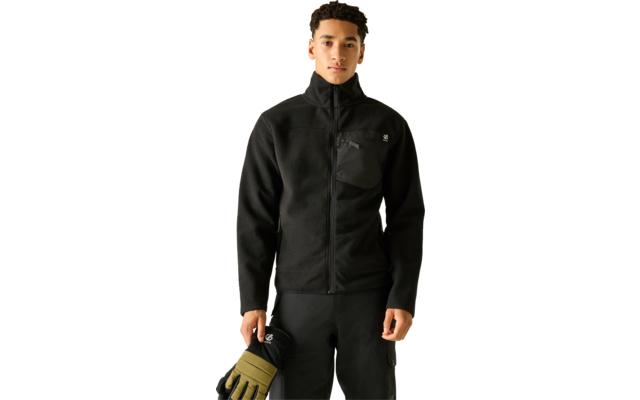 Mann frontal, schwarze Fleecejacke mit Reißverschluss und Brusttasche, schwarze Cargohose, hält olivgrüne Handschuhe in der rechten Hand; heller beiger Hintergrund