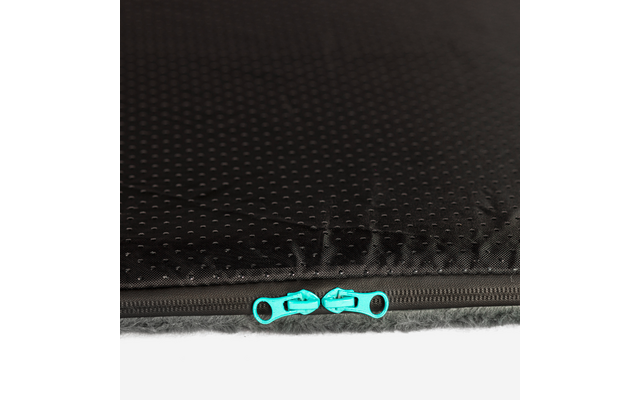 Nahaufnahme eines schwarzen, gepunkteten Stoffs mit einem geschlossenen Reißverschluss und zwei türkisen Zippern, unterer Rand zeigt graues Fell