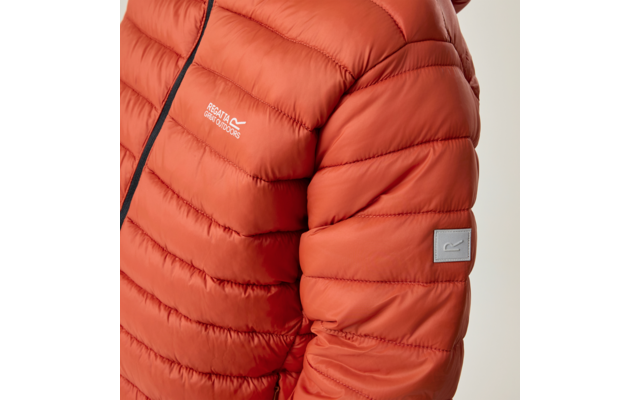 Nahaufnahme einer orangefarbenen Steppjacke mit horizontalen Steppnähten, sichtbarem schwarzen Reißverschluss, weißer Schrift "Regatta Great Outdoors" auf der Brust und rechteckigem Stoffpatch am Ärmel vor beigem Hintergrund