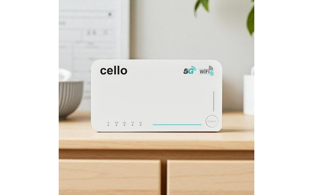 Weißes rechteckiges Gerät mit der Aufschrift "cello", 5G- und WiFi6-Symbole, Reihe von Status-LEDs und ein Power-Knopf, auf einer hellen Holzoberfläche; unscharfer Hintergrund mit Pflanze und Schale