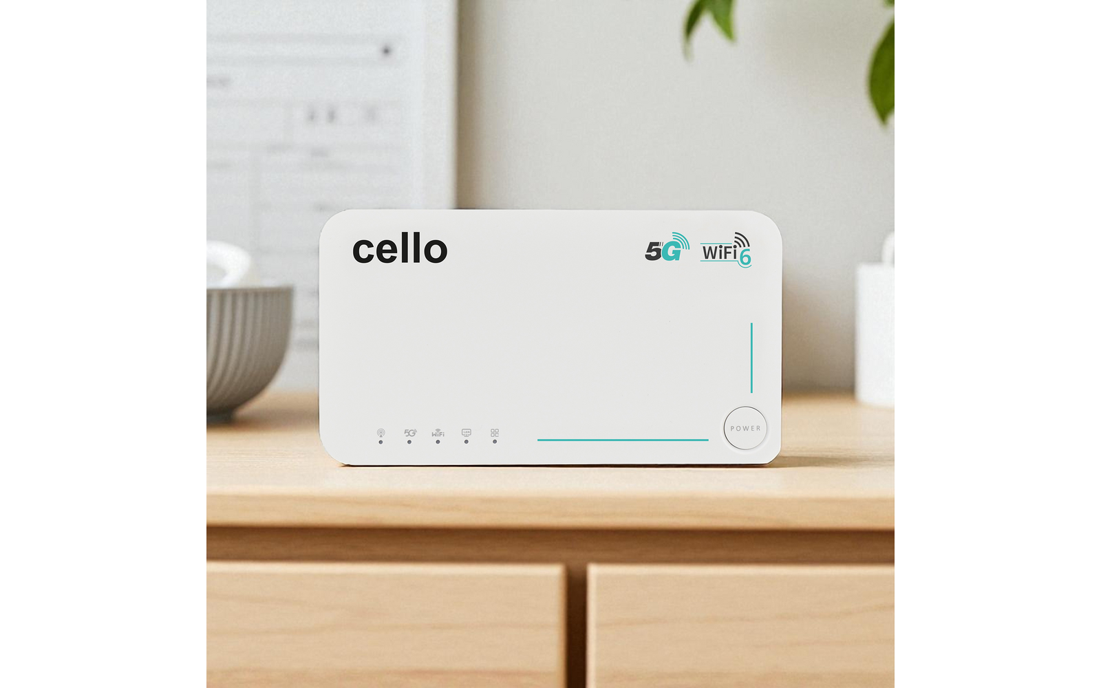 Weißes rechteckiges Gerät mit der Aufschrift "cello", 5G- und WiFi6-Symbole, Reihe von Status-LEDs und ein Power-Knopf, auf einer hellen Holzoberfläche; unscharfer Hintergrund mit Pflanze und Schale