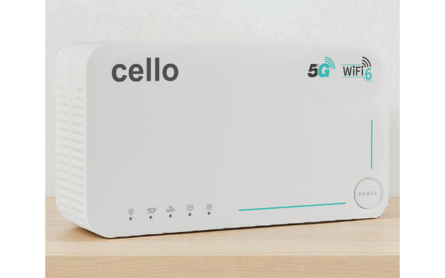 Weißes rechteckiges Gerät mit Schriftzug 'cello', 5G- und Wi‑Fi-Symbole, vertikale LED‑Leiste, runde Power‑Taste, kleine Kontrolllampen und Lüftungsöffnungen, auf einer Holzoberfläche